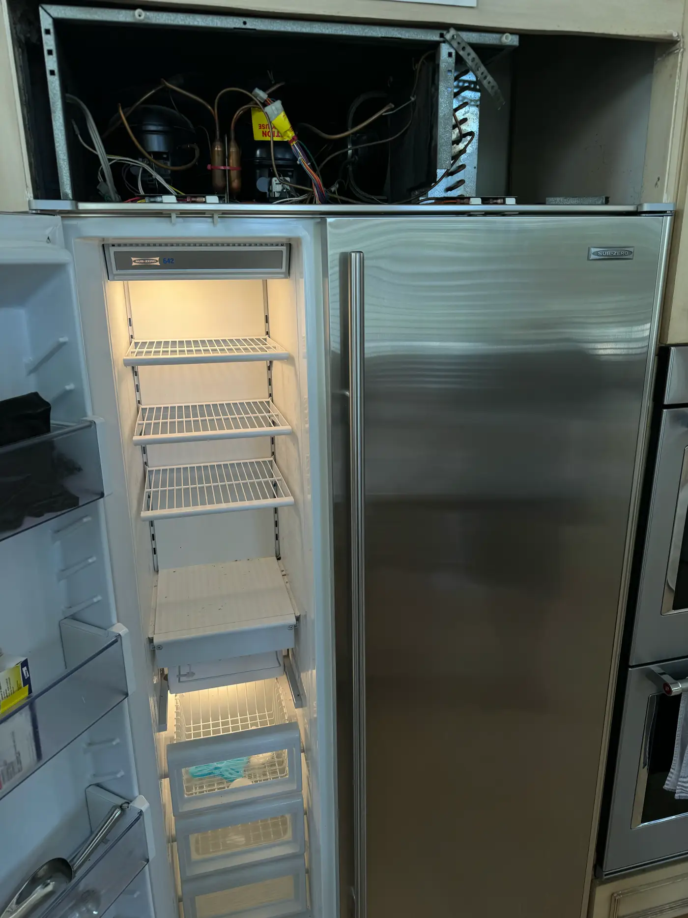 Built-in refrigerator with the compressor compartment opened during a sealed-system diagnosis