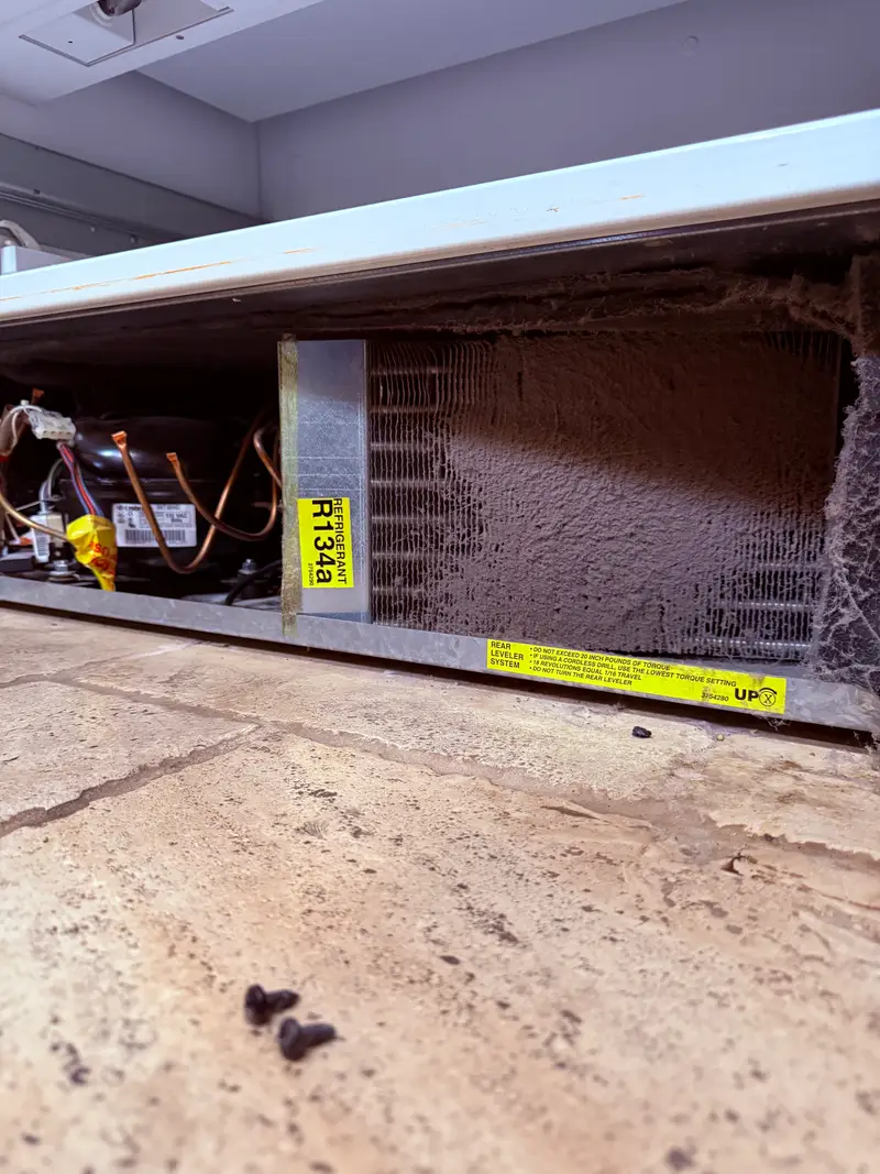 Condenser coil of a Sub-Zero built-in heavily blocked with dust before cleaning
