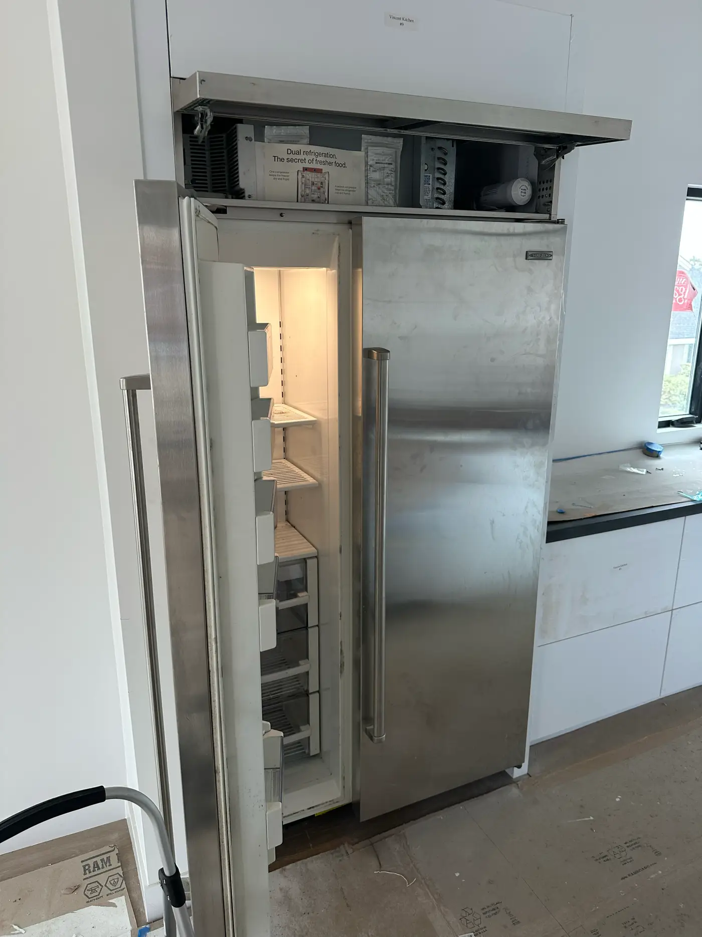 Sub-Zero built-in refrigerator with top compressor compartment open during installation service
