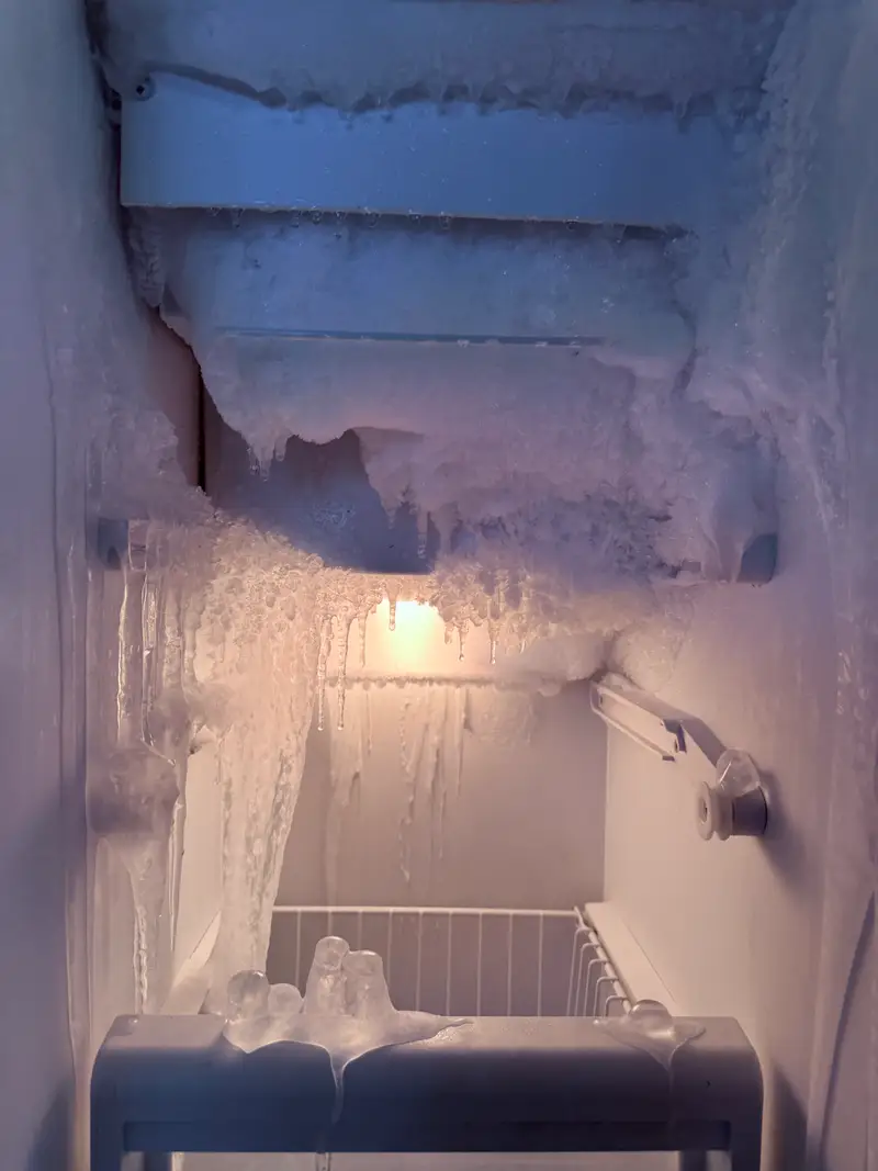 Heavy ice and icicles built up inside a Sub-Zero freezer compartment caused by a torn door gasket and a blocked drain