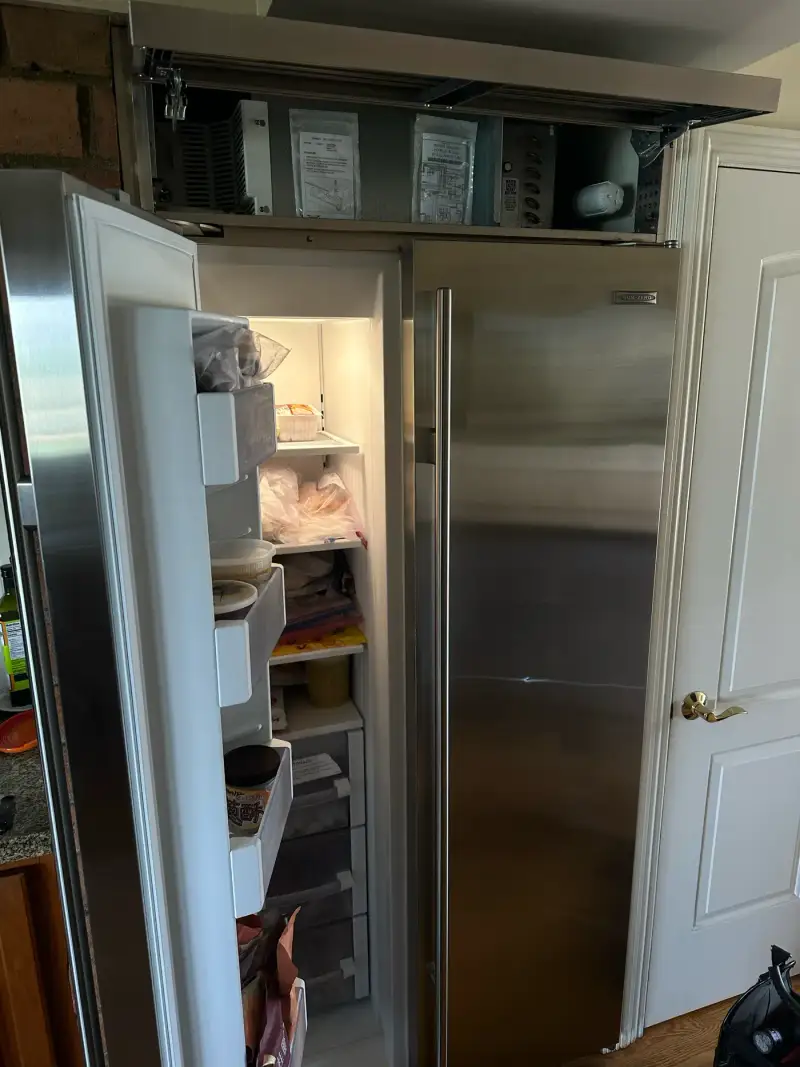 Sub-Zero built-in refrigerator with the top grille opened for condenser inspection