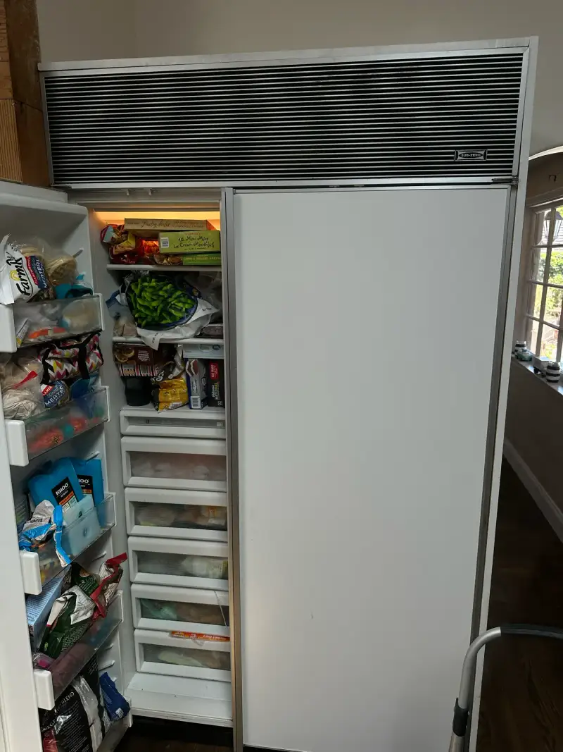 Older Sub-Zero built-in side-by-side refrigerator with the louvered grille during an ice maker repair
