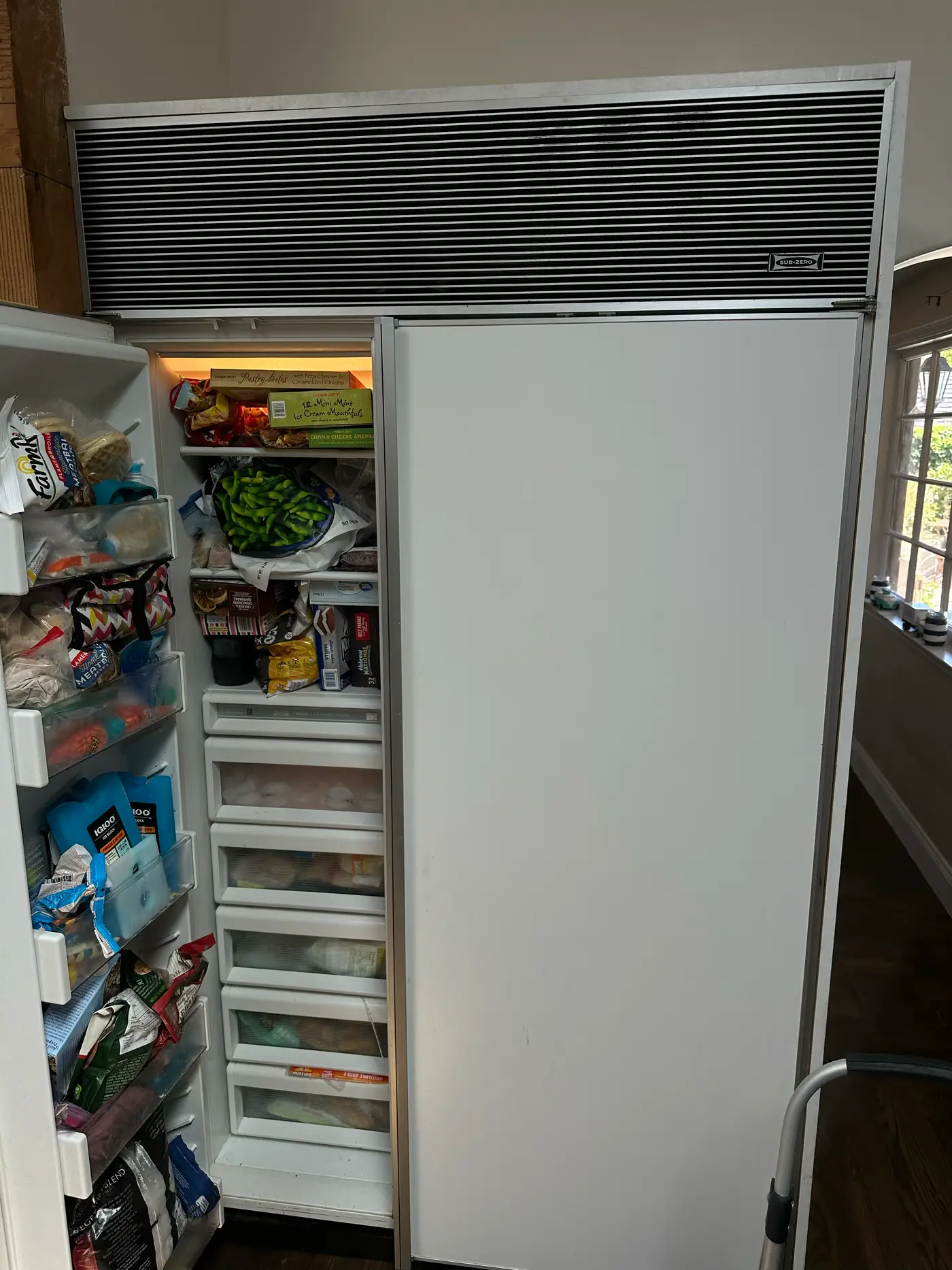 Older Sub-Zero built-in side-by-side refrigerator with the louvered grille during an ice maker repair