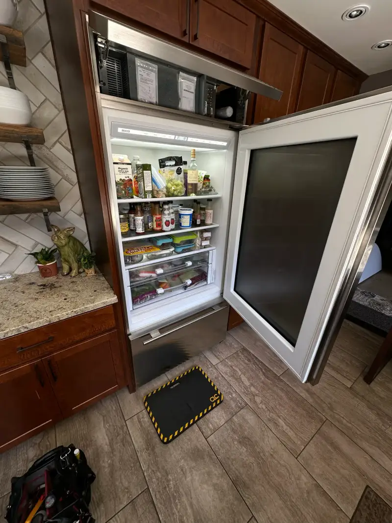 Panel-ready Sub-Zero over-and-under built-in refrigerator with the door open and top grille removed for service