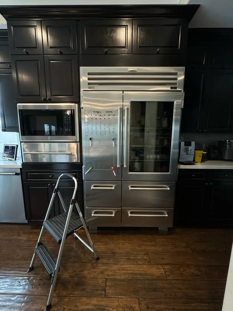 Sub-Zero PRO 48 glass-door refrigerator with a step ladder set up for an inspection and maintenance visit
