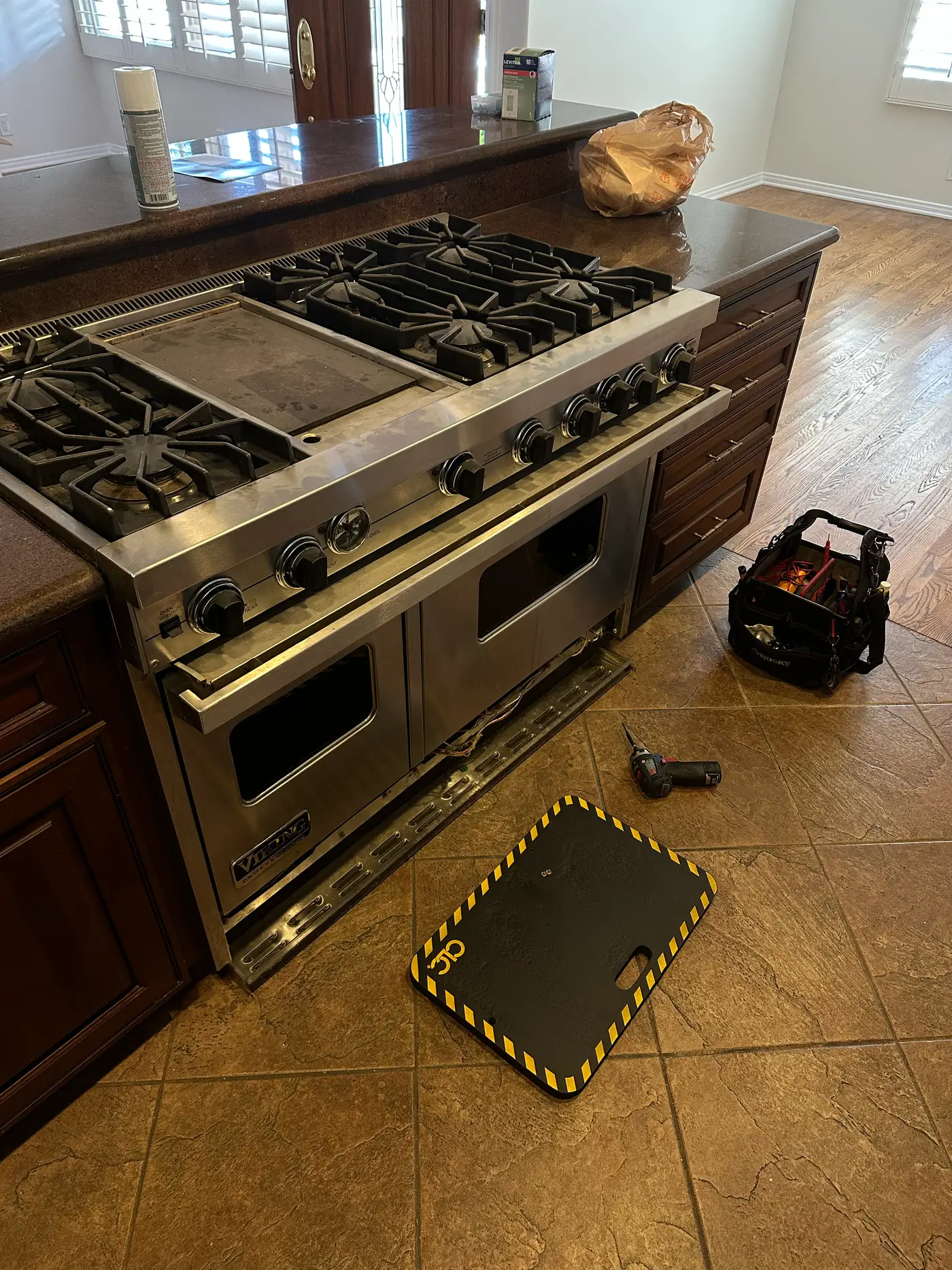Viking 48-inch professional range during service with technician tools and kneeling pad on the kitchen floor