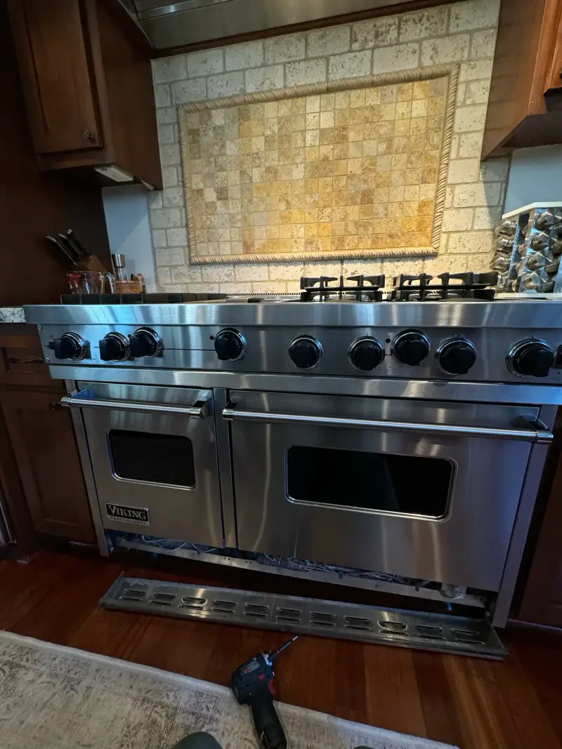 Viking 60-inch range mid-repair with the kick panel removed and tools on the floor