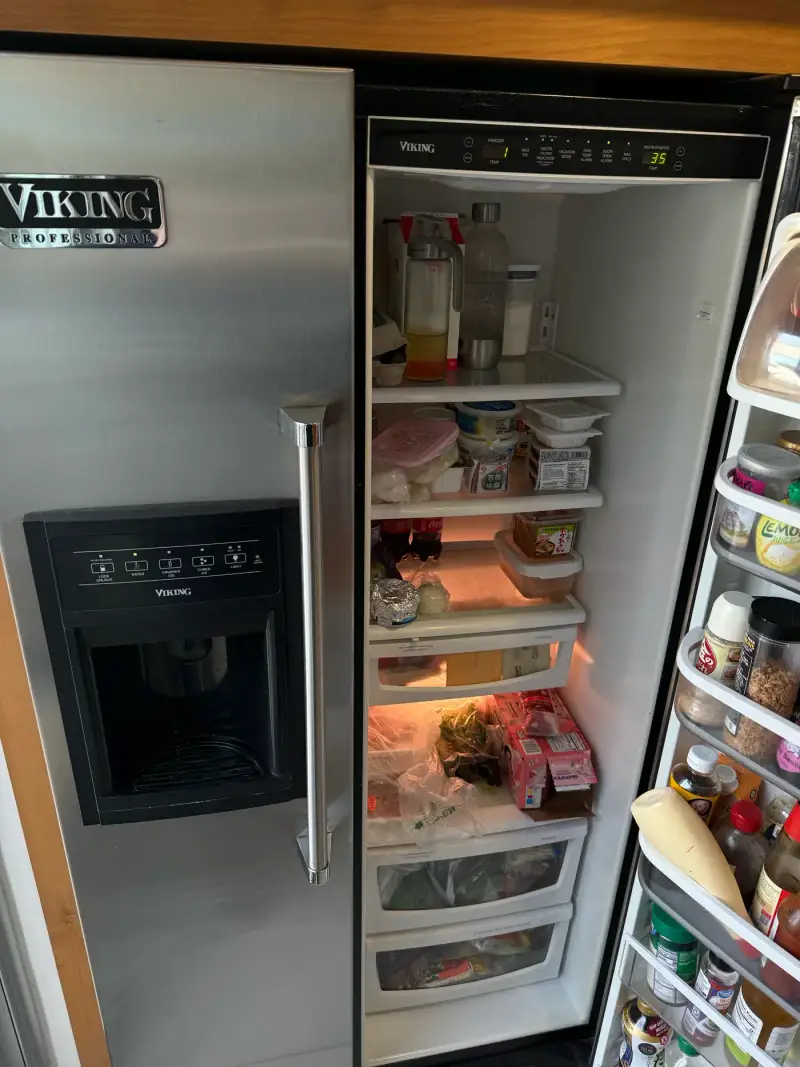 Viking Professional side-by-side refrigerator with doors open showing interior shelves and dispenser panel