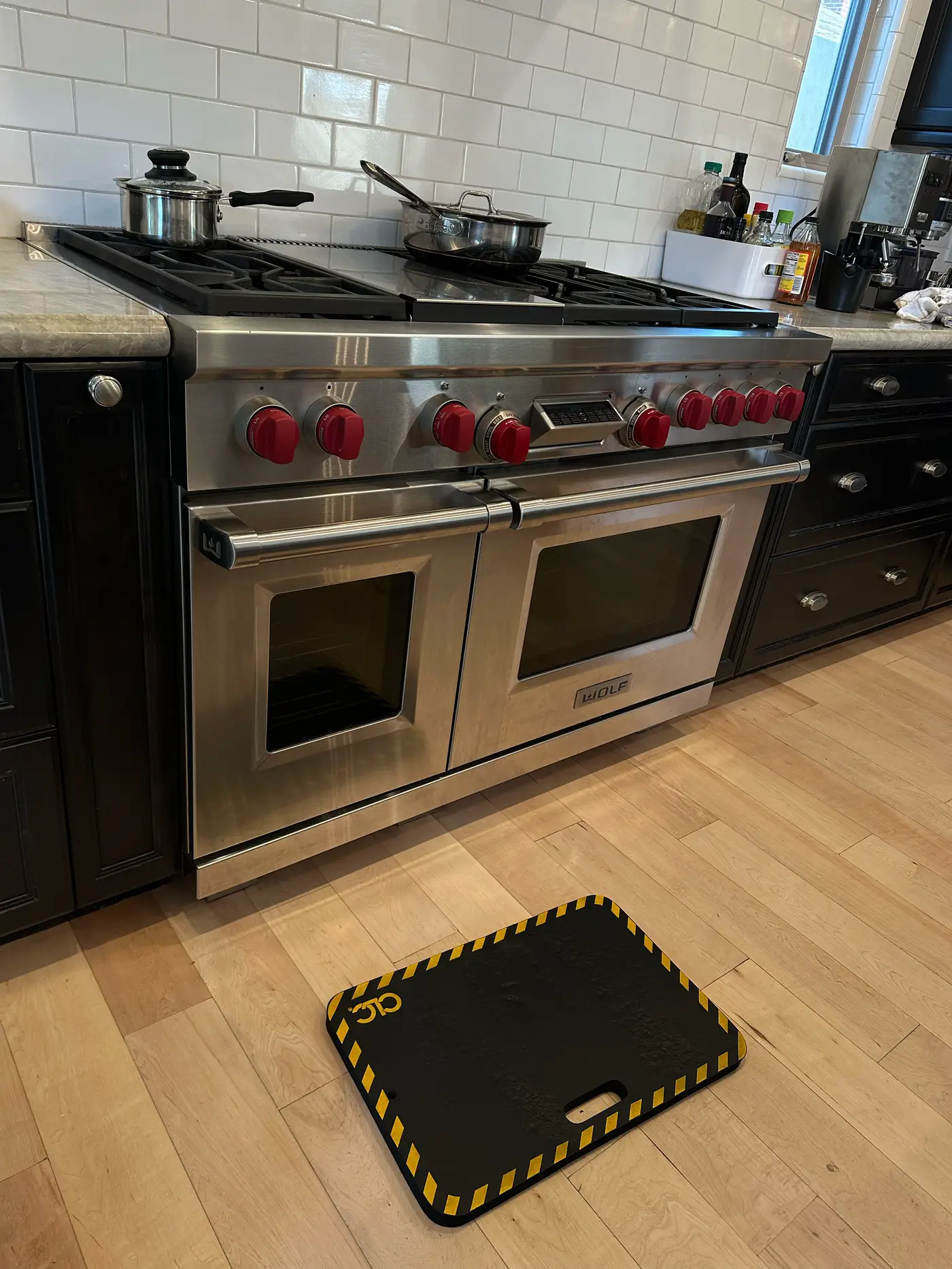 Wolf 48-inch dual-oven range with red knobs and a technician working at the control area