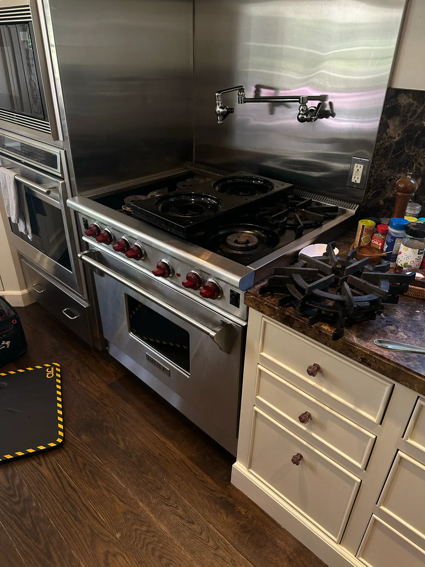 Wolf gas range with red knobs and burner grates partially removed during an igniter replacement