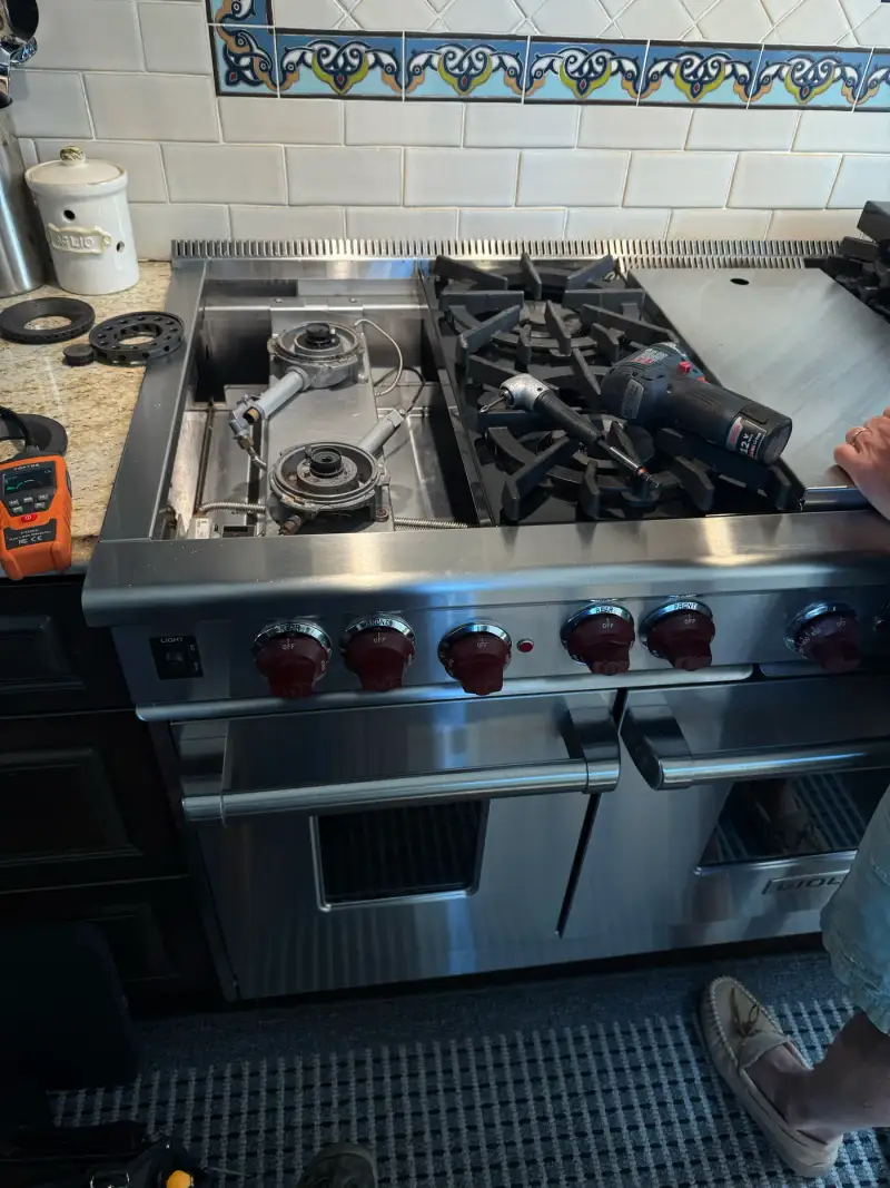 Wolf 48-inch range with the burner deck opened and ignition wiring exposed during a spark module replacement