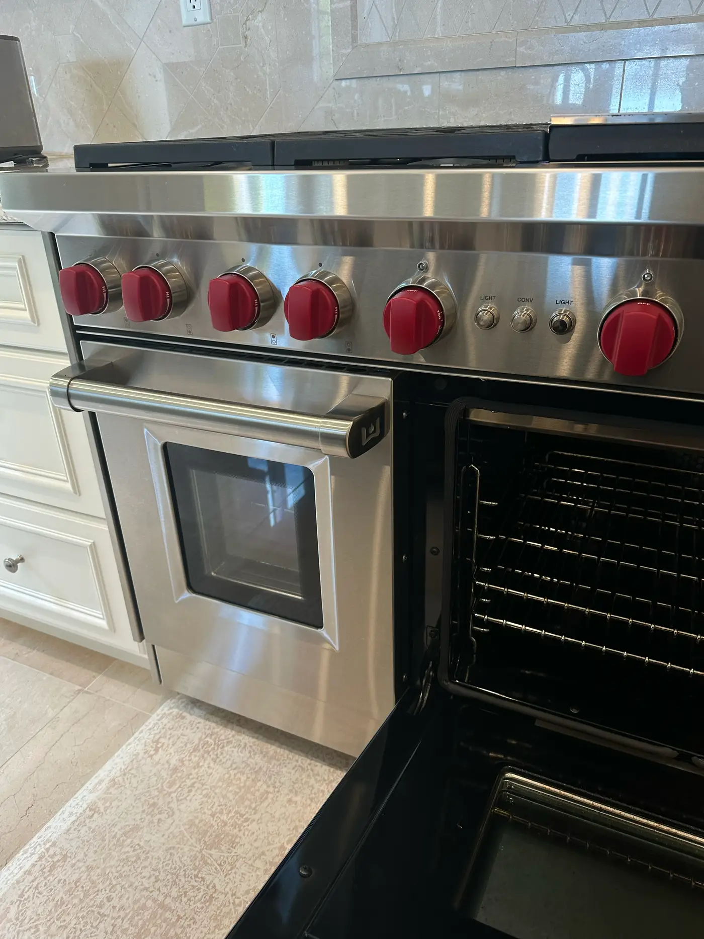 Wolf 48-inch range with red knobs and open oven door, close-up